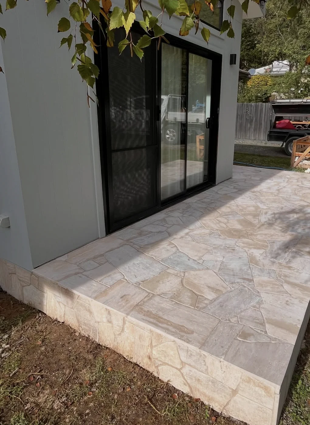 Silver travertine paving beside a contemporary home in Montrose